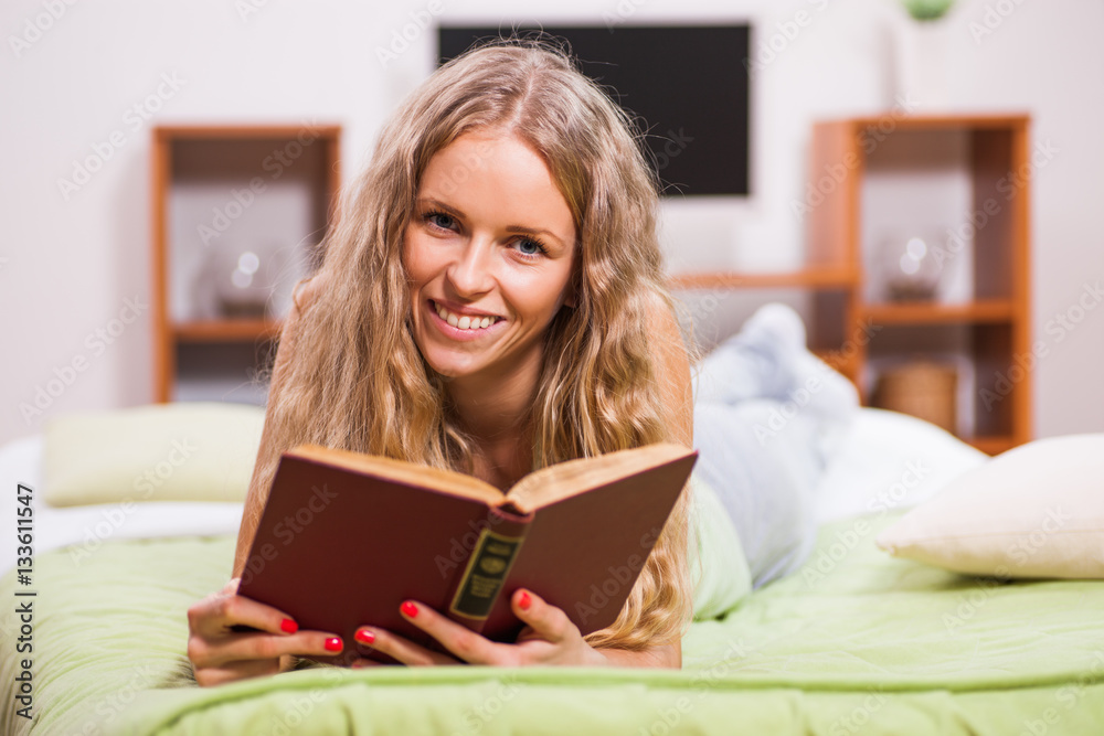 Young woman is lying in bed and reading book. Young woman is lying in bed and reading book.