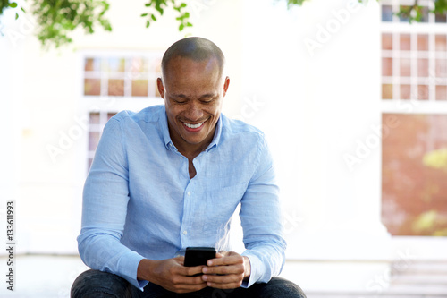 cool african guy sitting outside with cellphone