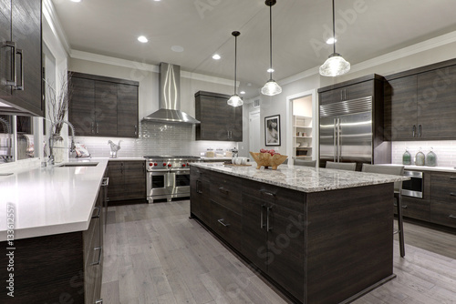 Modern gray kitchen features dark gray flat front cabinets paired with white quartz countertops and a glossy gray linear tile backsplash. Northwest, USA. photo