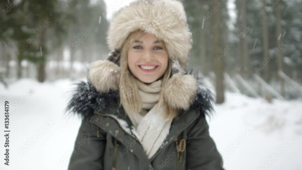 Portrait of smiling woman enjoying wintertime. Woman wearing warm clothes in a cold winter snow forest. Trees on background. Shot on Red Epic. Portrait of smiling woman enjoying wintertime. Woman wearing warm clothes in a cold winter snow forest. Trees on background. Shot on Red Epic.