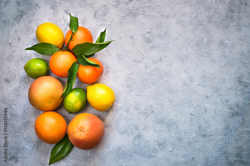 Different citrus fruit on grey concrete table. Orange lime lemon tangerines. Top view