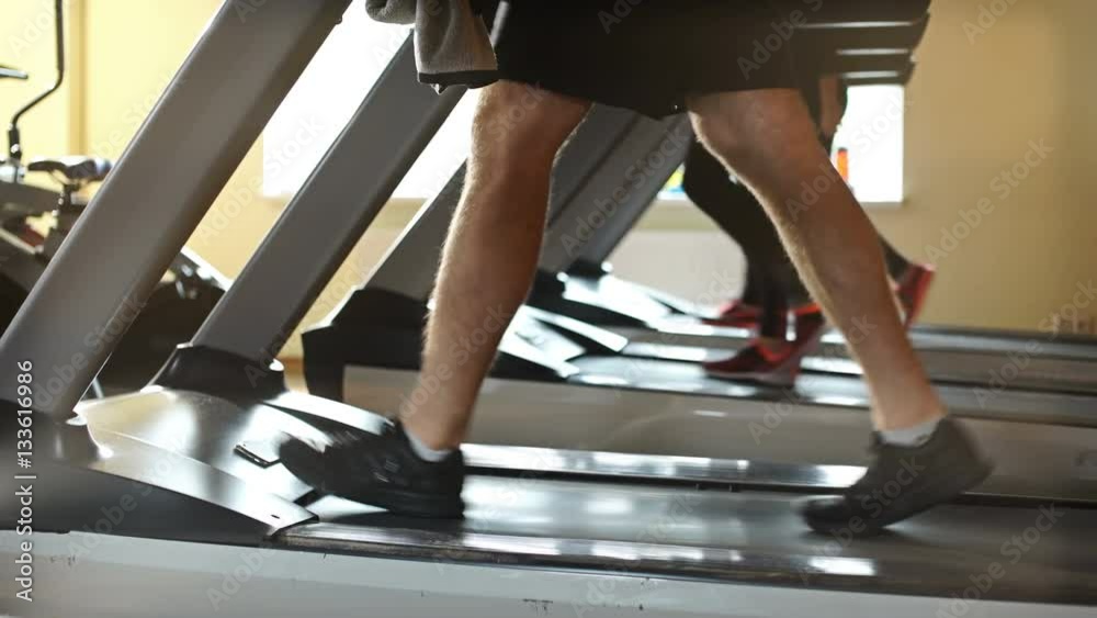 Part of man in sports shoes running on treadmill at gym Part of man in sports shoes running on treadmill at gym