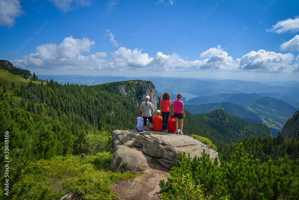 Group of young hikers sitting on a cliff edge in the Ceahlau mountains in Romania