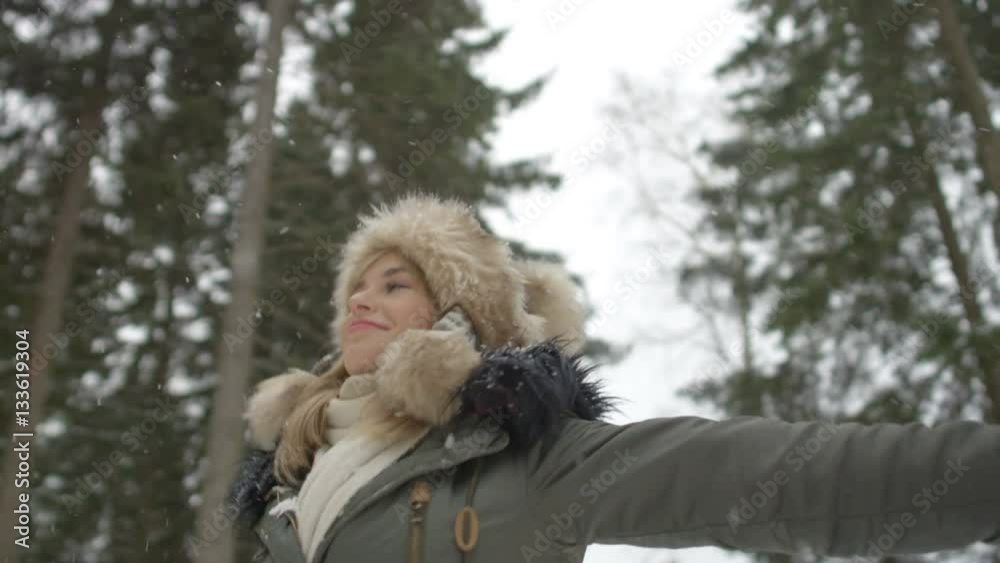 Portrait of smiling woman enjoying wintertime. Woman wearing warm clothes in a cold winter snow forest. Trees on background. Shot on Red Epic. Portrait of smiling woman enjoying wintertime. Woman wearing warm clothes in a cold winter snow forest. Trees on background. Shot on Red Epic.