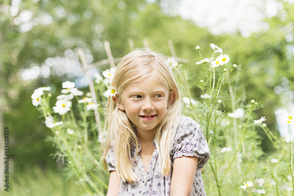 Young blonde girl with flowers in background Young blonde girl with flowers in background