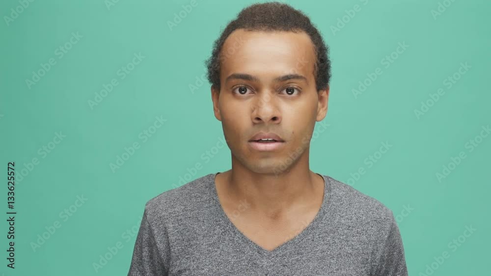 Young disappointed afro american man looking at camera isolated on the green background Young disappointed afro american man looking at camera isolated on the green background