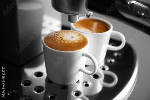 Two cups with fresh espresso in new coffee maker, closeup