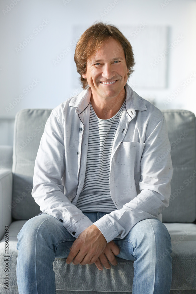 Mature man sitting on sofa at home