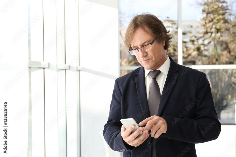 Successful mature man with mobile phone in office Successful mature man with mobile phone in office