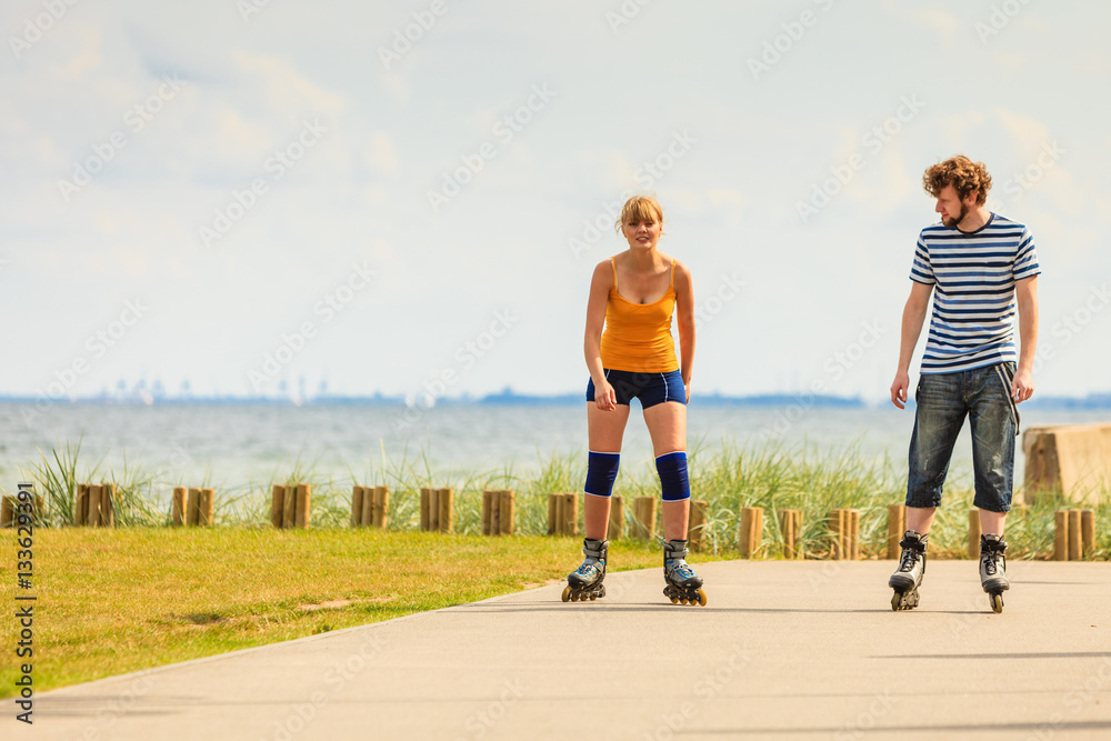 Fototapeta premium Young couple on roller skates riding outdoors