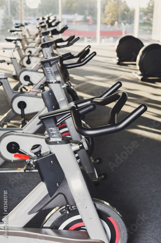 Modern gym interior with equipment, fitness exercise bikes handlebars