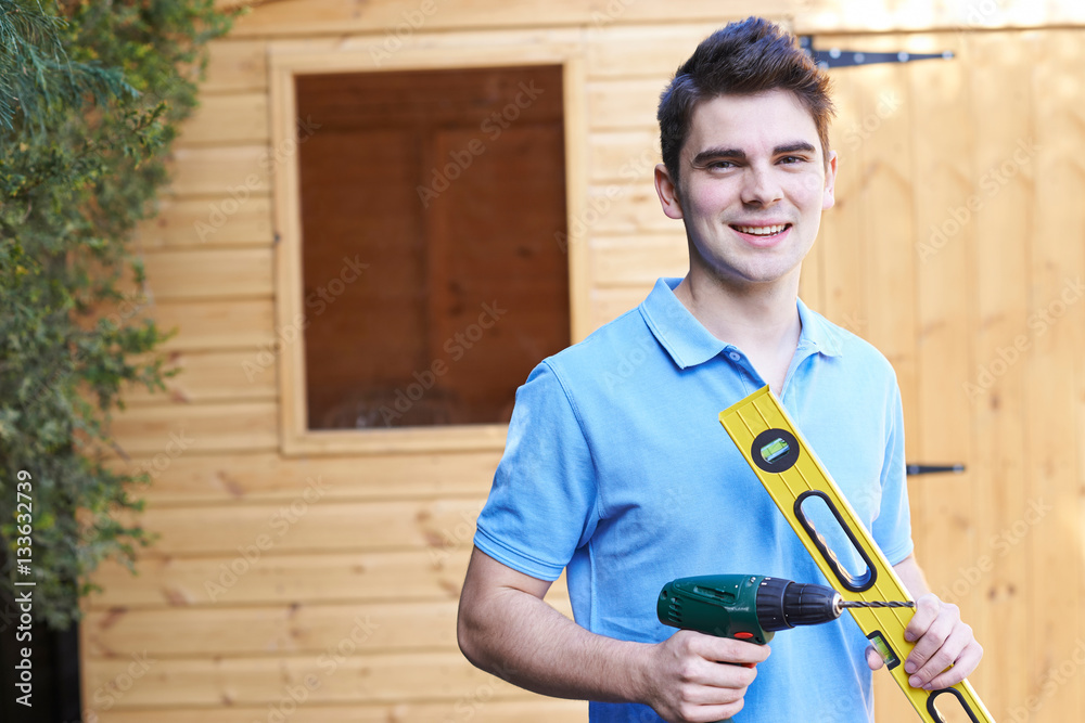 Fototapeta premium Handyman Standing Outside Garden Shed With Tools
