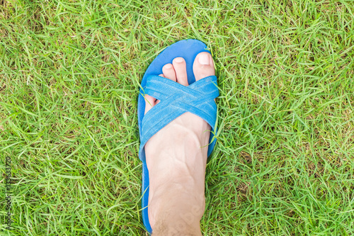 left foot with slippers on green grass in park for green ecology concept © jirakit