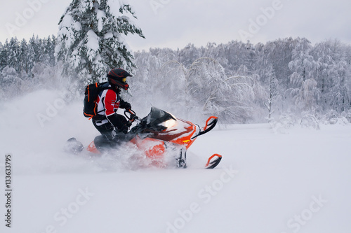 Athlete on a snowmobile moving in the winter forest