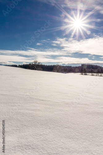 Die Wintersonne erstrahlt über den verschneiten Feldern im Voralpenland