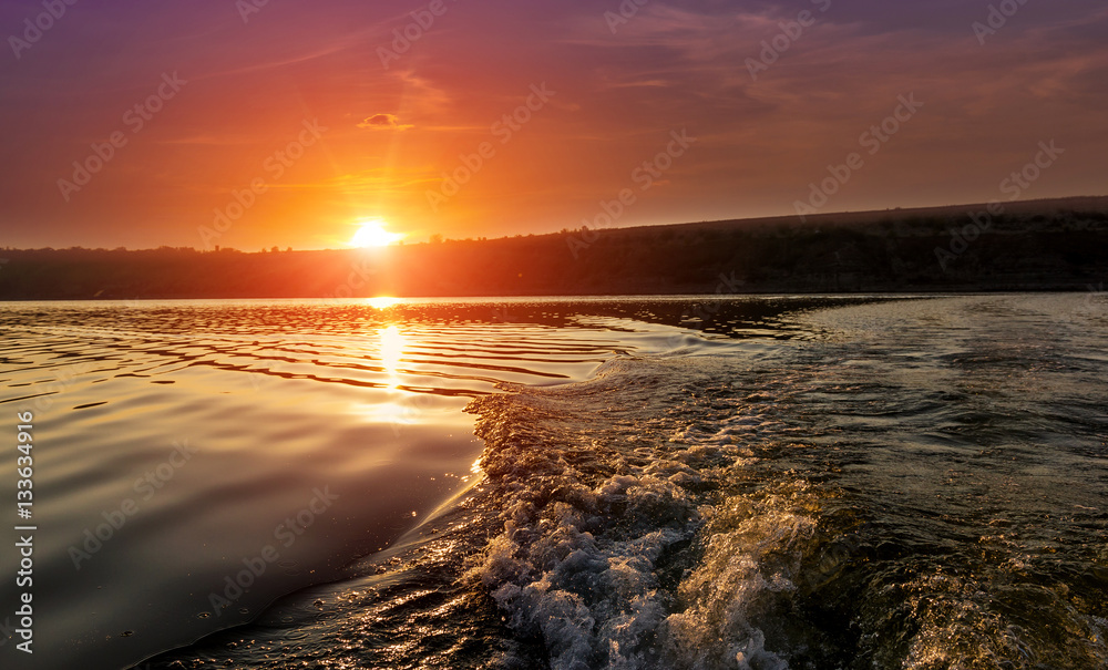 close-up texture of waves on the river at sunset, the trail from the boat. colorful clouds on the sky over the morning river. majestic misty sunrise. Beauty in the world. Ukraine.  Dniester