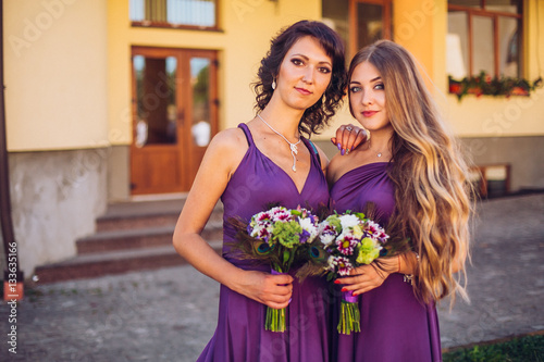 young and beautiful bridesmaids in violet dress standing outdoors