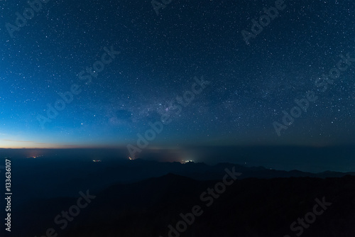 Stars illuminated above the dark silhouette mountain before sunrise.