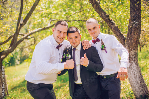 groom with groomsmen have fun in the park on the wedding. Wedding guest friends.