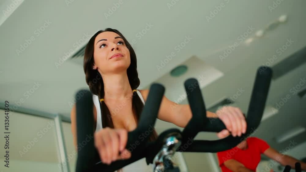 Young beautiful woman cycling on the exercise bike in the gym Young beautiful woman cycling on the exercise bike in the gym