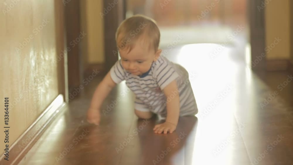 Cute toddler boy crawling on wooden floor at house Cute toddler boy crawling on wooden floor at house