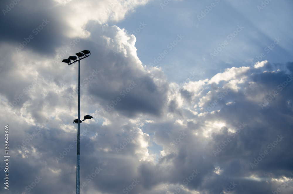 Blue sky breaking through clouds near light pole