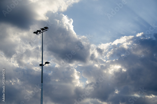 Blue sky breaking through clouds near light pole