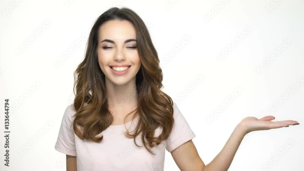 Beautiful young woman holding copy space and smiling while standing isolated on white Beautiful young woman holding copy space and smiling while standing isolated on white