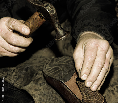 Shoemaker is repairing shoe.Retro style toned image.