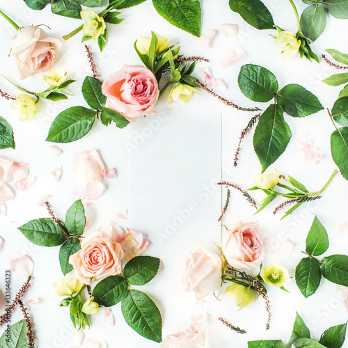 Frame of blank paper, pink roses, branches, leaves and petals isolated on white background. Flat lay, top view