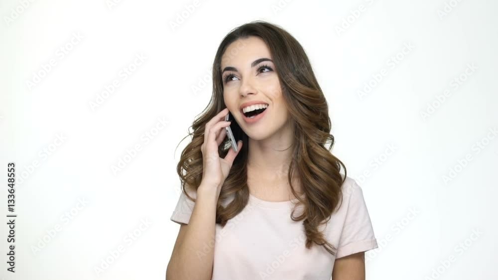 Smiling young woman talking on mobile phone and showing thumbs up gesture isolated on white Smiling young woman talking on mobile phone and showing thumbs up gesture isolated on white