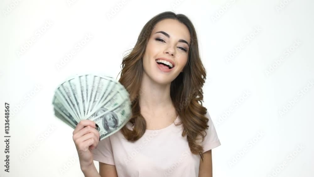 Happy young woman holding money in her hands and looking at camera while standing isolated on white Happy young woman holding money in her hands and looking at camera while standing isolated on white