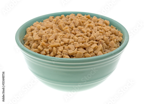 Toffee bits in a green bowl on a white background.