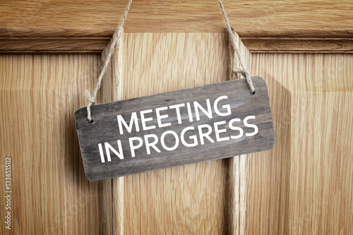 Meeting in progress sign on office door photo