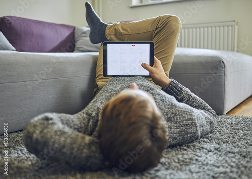 Man laying on floor and looking at tablet photo