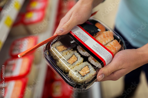 hands with sushi pack at grocery or supermarket