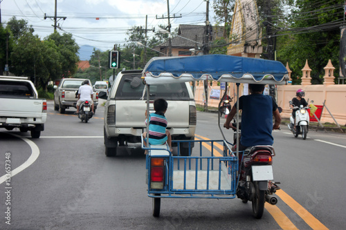 The little boy sitting in the local modified motorcycle on the roads in Thailand. 