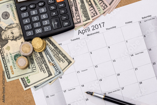 calendar with tax due date and us money, pen, calculator. April 2017.