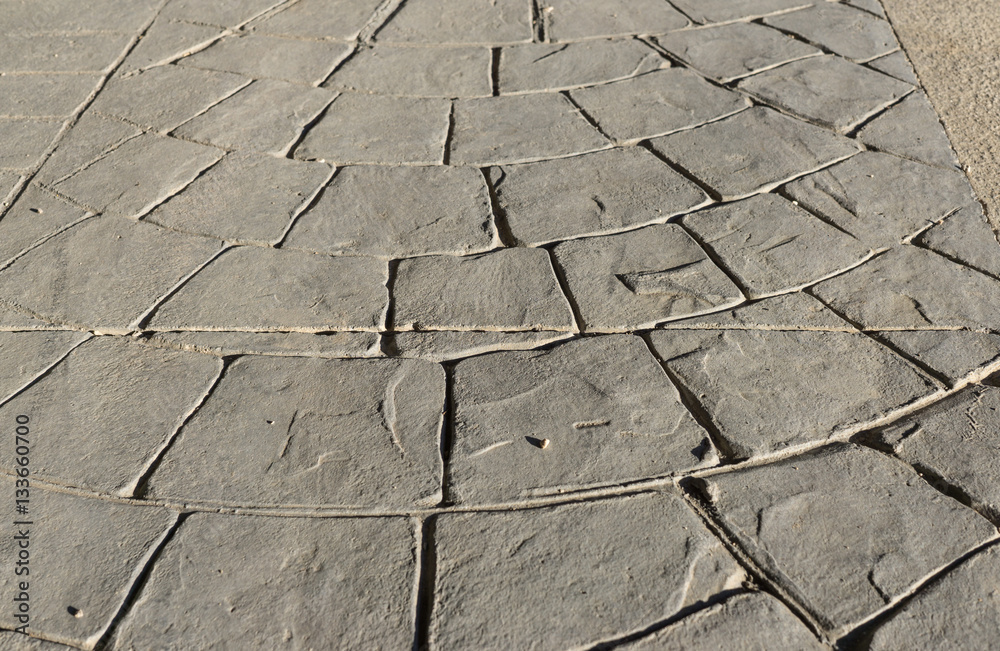 Stamped concrete pavement outdoor an expansion joint in the middle, mimics cobblestones circular