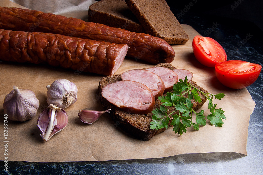 Slices of smoked sausage with spice, herbs and vegetables on the Slices of smoked sausage with spice, herbs and vegetables on the