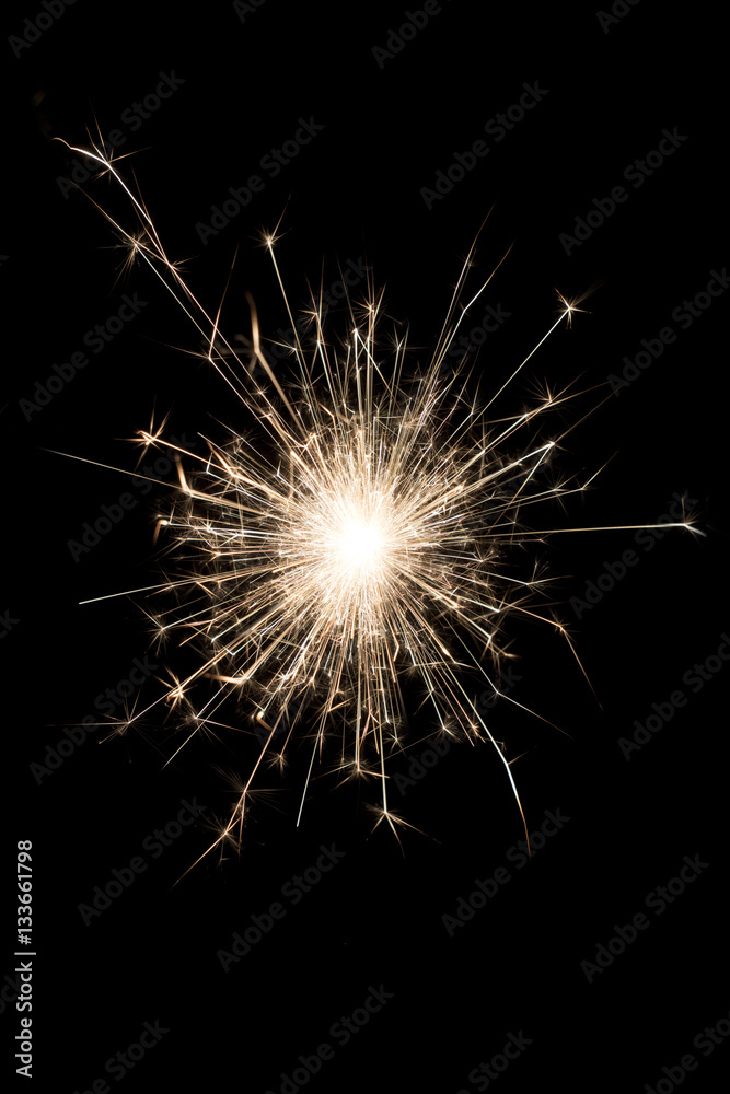 A burning sparkler on a black background