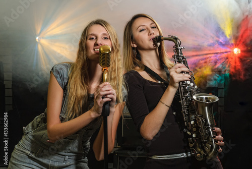 Sticker Attractive women playing on saxophone and with microphone at music concert