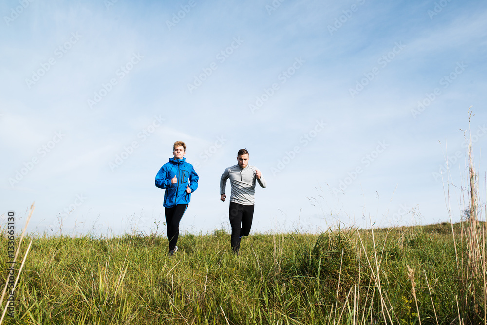Two young hipster athletes running in sunny autumn nature Two young hipster athletes running in sunny autumn nature