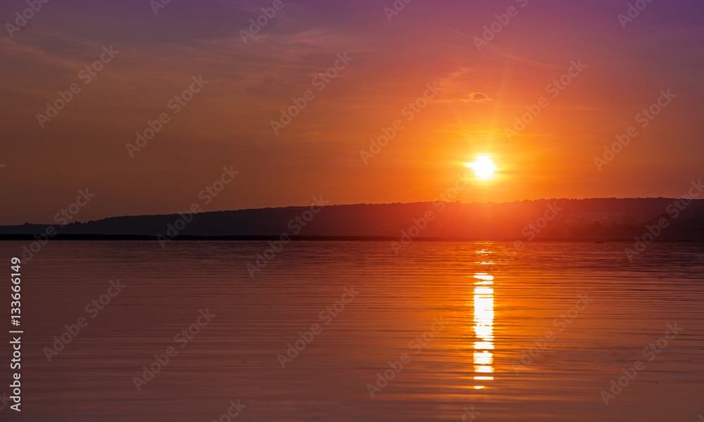 sunset over the lake. sun reflected in water. unusual picturesque scene. beauty in the world