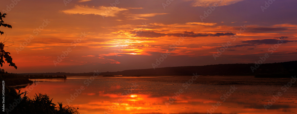 Colorful warm sunset over the evening lake. clouds on the sky reflected in water. Artistic style. creative images. majestic, wonderful landscape. beauty of the world