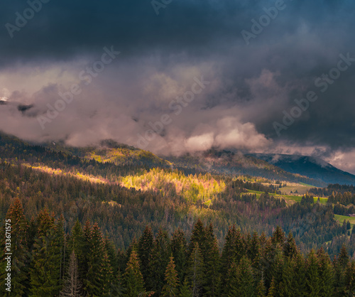 Beautiful dramatic clouds over mountains. Sunlight spots on the forest hills at Carpathian mountains. Ukraine.