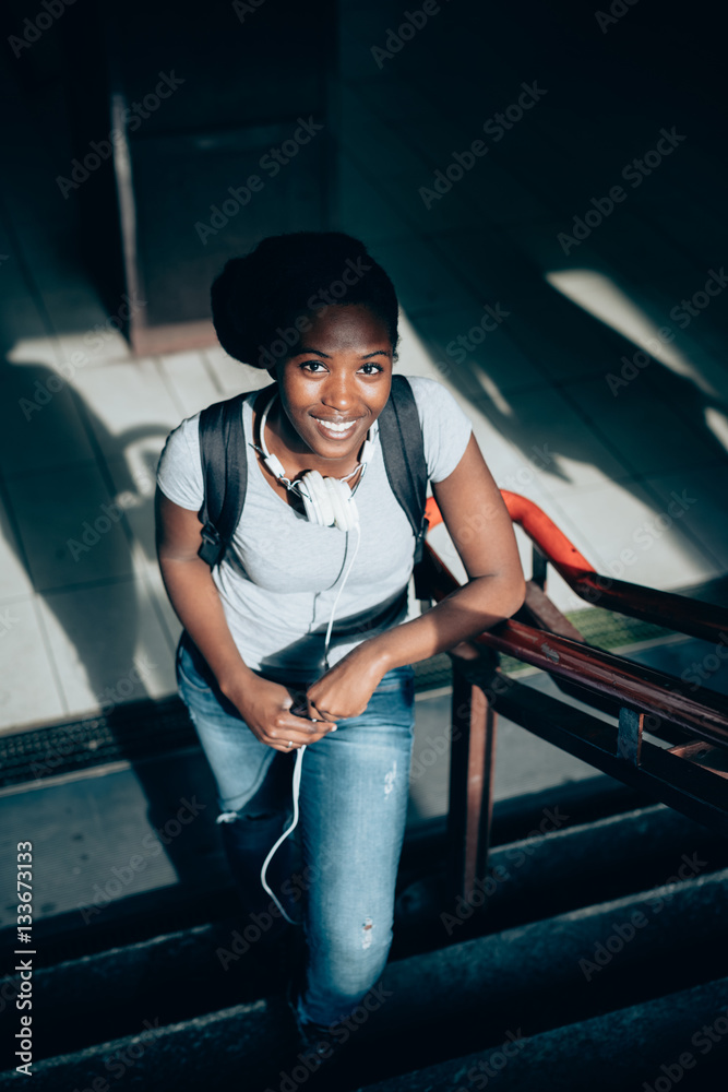 Young black beautiful woman walking upstairs from underground using smart phone hand hold - technology, social network, communication concept Young black beautiful woman walking upstairs from underground using smart phone hand hold - technology, social network, communication concept