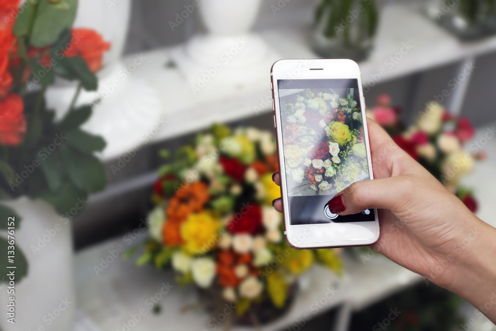 Female hand taking photo of beautiful flowers with smart phone at floral shop Female hand taking photo of beautiful flowers with smart phone at floral shop