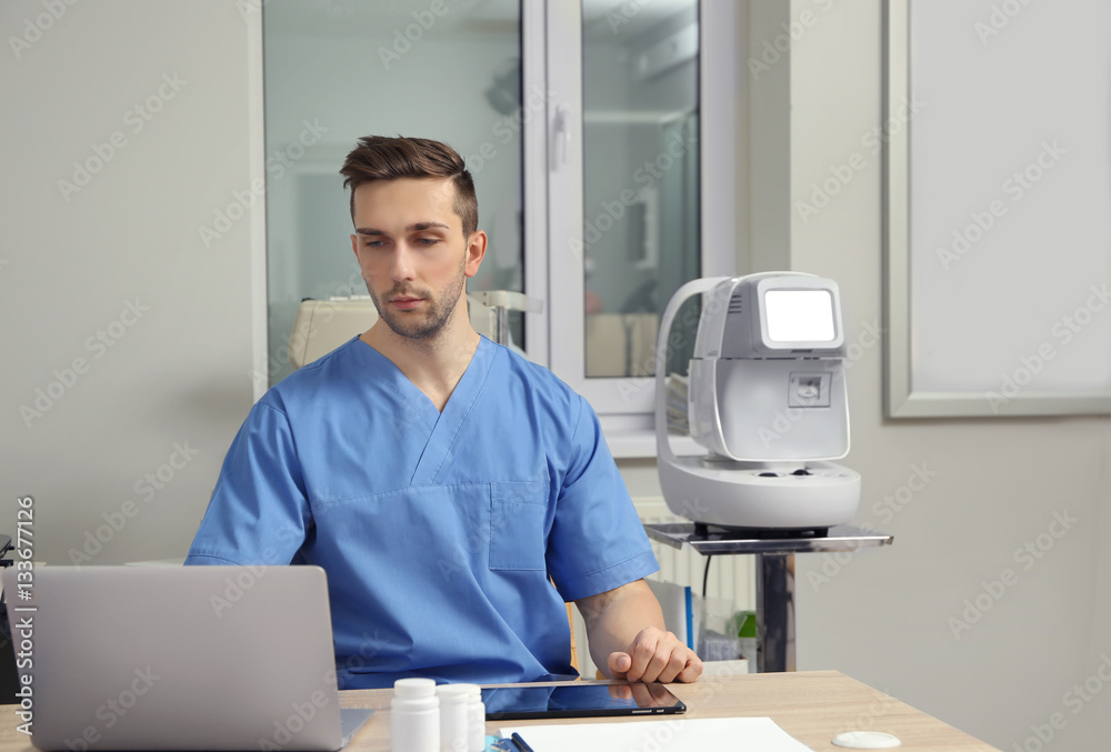 Handsome young ophthalmologist working in office Handsome young ophthalmologist working in office