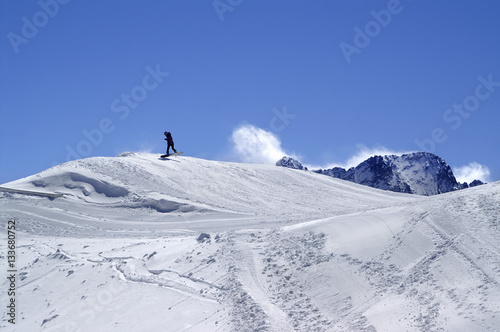 Snowboarder in terrain park at ski resort on sun winter day